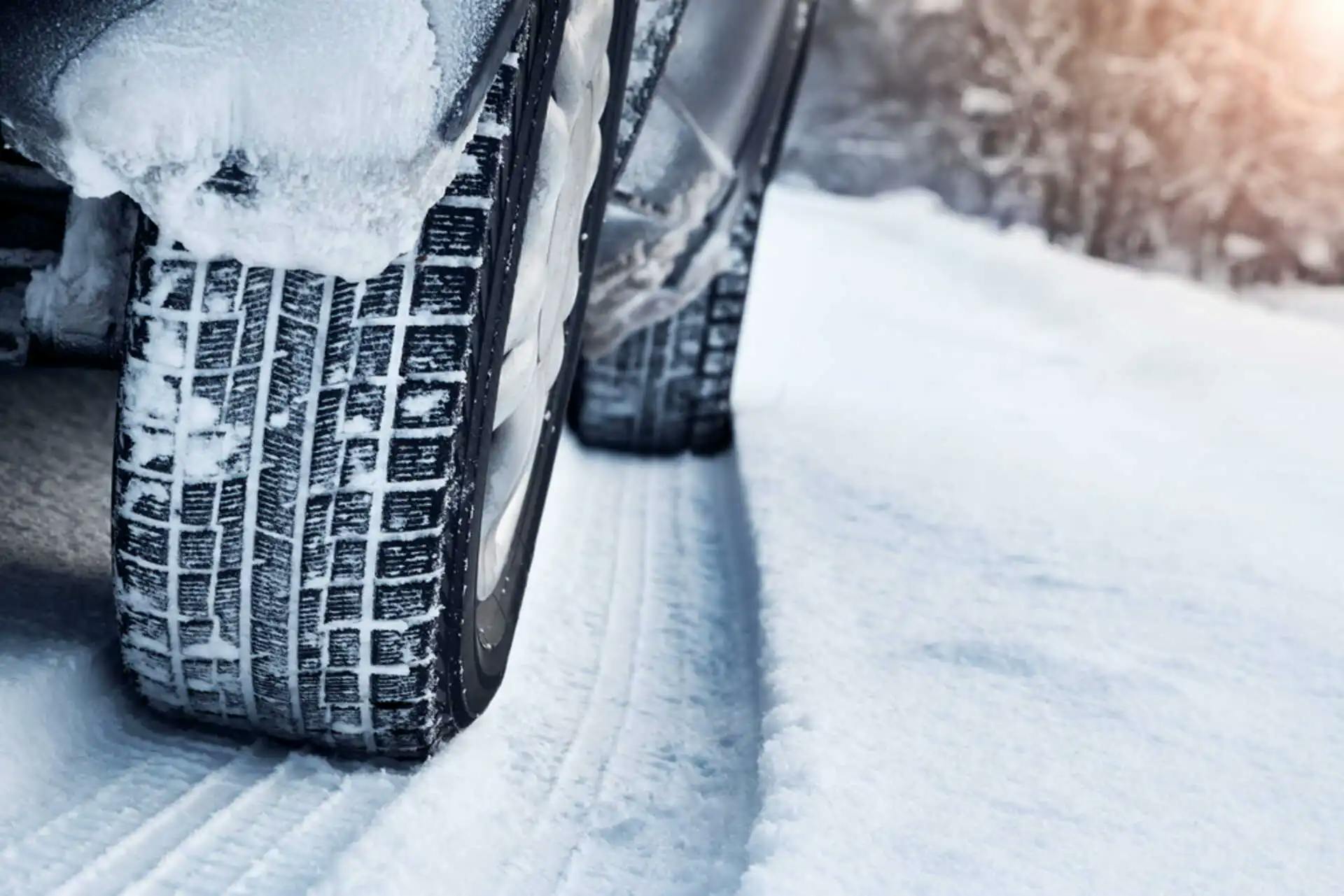Voiture qui roule sur de la neige avec un zoom sur les pneus